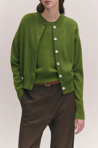 front profile model wearing Ada Crew Neck Cardigan Green lambswool relaxed fit crewneck with white buttons