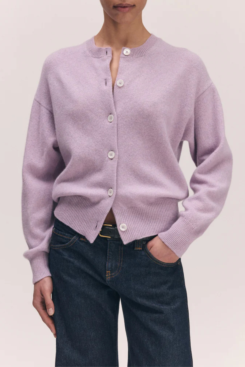front profile model wearing  Ada Crew Neck Cardigan Pansy Purple lambswool crewneck long sleeve white button closure ribbed cuff and hem