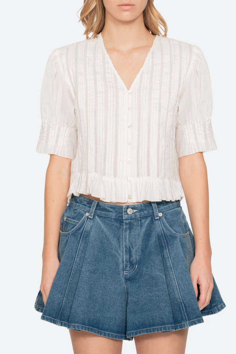 front profile model wearing Alberte Top white cotton V-neckline
Short sleeves
Delicate pintuck pleats
Subtle peplum hem
button front
