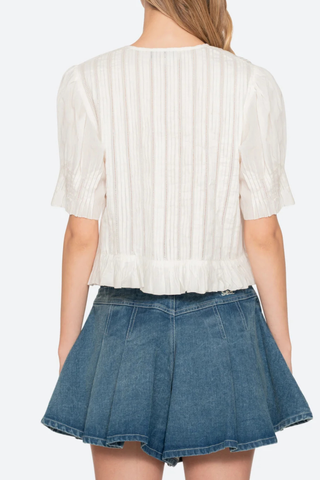 back profile model wearing Alberte Top white cotton V-neckline
Short sleeves
Delicate pintuck pleats
Subtle peplum hem
button front