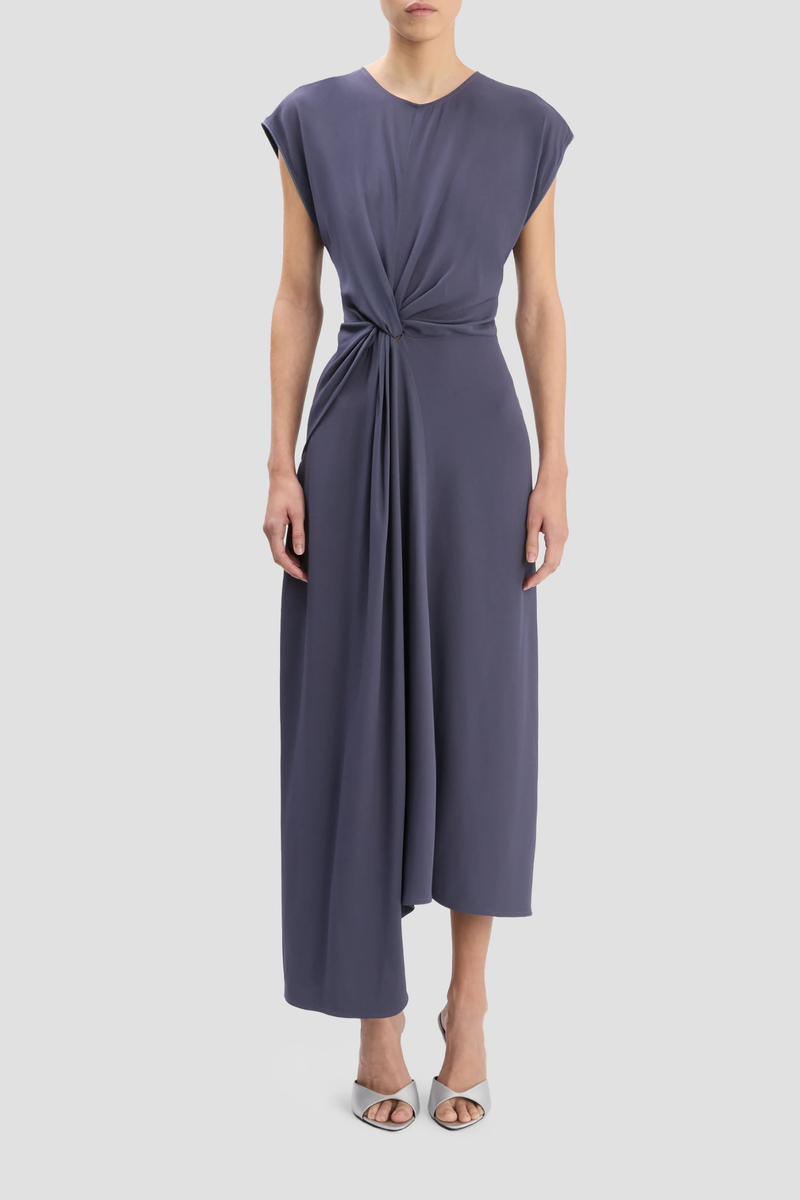 front profile model wearing Aria Twist Waist Dress eclipse muted blue grey Ankle length with asymmetric hem
Drape fabrication
Round front neckline
V-shape back
Cap sleeve
Twist waist
Concealed zip with hook &amp; eye closure
