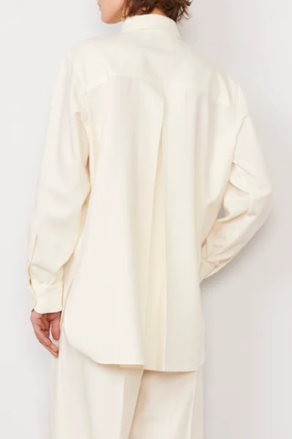 back profile model wearing Auria Shirt Italian Twill Shirt ivory Loose-fit
Long-sleeve
Sharp shirt collar
100% Virgin wool
Button closure
Buttoned cuffs with cuff placket
Back yoke with an inverted pleat
Gathers at the cuffs
Curved hem with a longer back than front.
Cover buttons