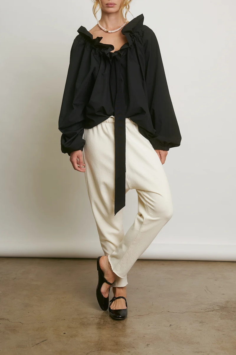 front profile model wearing  Beautiful Mess Top Black Bow neck
puff sleeves
Grand ruffle neck cinched in with lovely wide ribbon
Long sleeve
Elastic cuff
Straight hem

Relaxed fit
100% Cotton