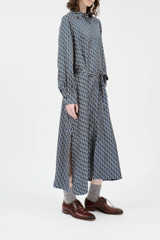 side profile model wearing Button Down Long Sleeve Silk Dress admiral blue geometric mini pattern attached waist tie high side slit hidden button closure midi length
