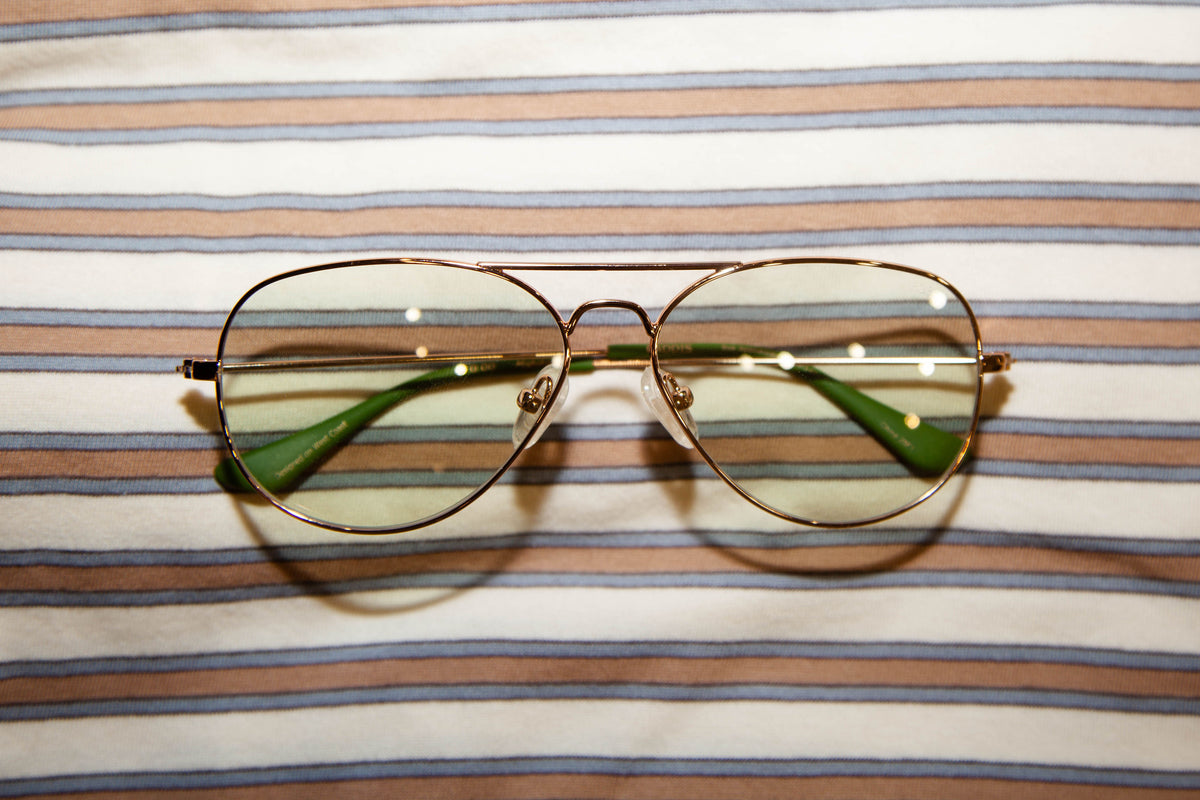 green tinted aviator glasses with orange blue and white horizontal stripe background