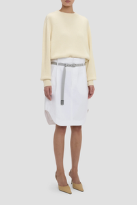 side profile model wearing Cargo Skirt optic white A-line shape
Mid rise
Knee length
Zip fly with double hook &amp; bar closure
Self fabric waistband with internal trim
Belt loops
Button closed pocket
100% Cotton