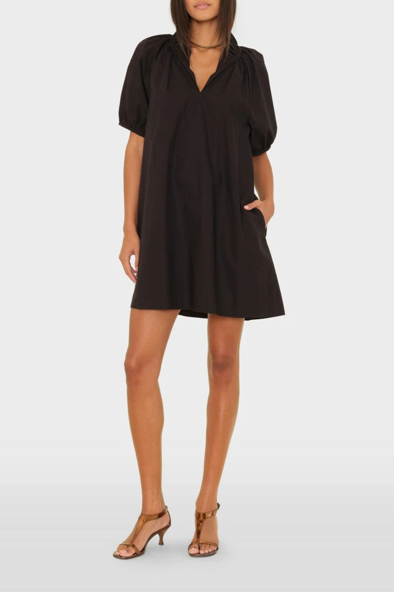 front profile model wearing Carleigh Ruffle Neck Dress Black cotton Crisp paper poplin with a refined feel
Mini dress
Deep V-neck
Ruffle detailing
Shirred puff sleeves
Side seam pockets