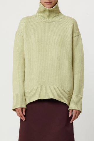 front profile model wearing Cashmere T-neck Sweater Cashmere T-neck Sweater pistachio, green Ribbed turtleneck, 
Ribbed cuff and hem, Relaxed fit