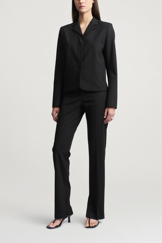 front profile model wearing Charlie Tropical Wool Long Trouser black Slim leg
Straight tailored trouser
Tropical wool suiting
Split hem
Mid-rise
Extended hook
Button tab closure at the waist
Belt loops
Side seam pockets
Sharp center front crease
Single back welt pocket