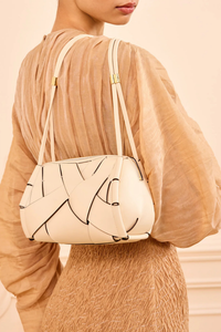 model wearing Charlotte Camera Bag Cowrie cowrie white
Hand-woven
Thick tubular strap
Worn crossbody or on the shoulder
Suede interior
Calfskin nappa leather
Hammered antique brass sliders
Zipper along top