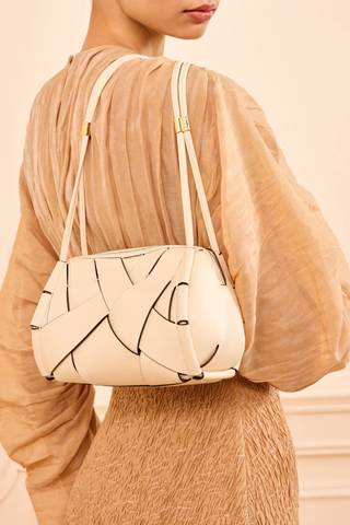 model wearing Charlotte Camera Bag Cowrie cowrie white
Hand-woven
Thick tubular strap
Worn crossbody or on the shoulder
Suede interior
Calfskin nappa leather
Hammered antique brass sliders
Zipper along top