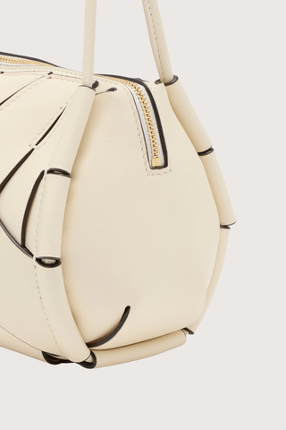 close up detail of Charlotte Camera Bag Cowrie cowrie white
Hand-woven
Thick tubular strap
Worn crossbody or on the shoulder
Suede interior
Calfskin nappa leather
Hammered antique brass sliders
Zipper along top