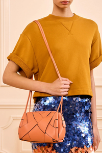 model wearing Charlotte Camera Bag Rose 
Hand-woven
Smooth white leather
Thick tubular strap
Worn crossbody or on the shoulder
Suede interior
Calfskin nappa leather
Hammered antique brass sliders
Zipper along top