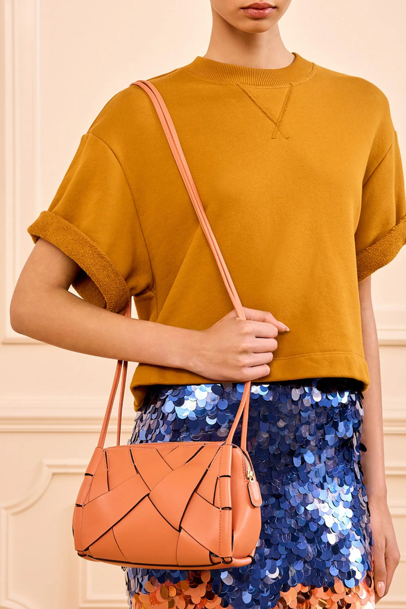 model wearing Charlotte Camera Bag Rose 
Hand-woven
Smooth white leather
Thick tubular strap
Worn crossbody or on the shoulder
Suede interior
Calfskin nappa leather
Hammered antique brass sliders
Zipper along top