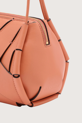 close up detail of Charlotte Camera Bag Rose 
Hand-woven
Smooth white leather
Thick tubular strap
Worn crossbody or on the shoulder
Suede interior
Calfskin nappa leather
Hammered antique brass sliders
Zipper along top