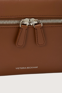 close up zipper and logo detail for Vanity Crossbody Bag tan 
Top handle
Removable crossbody strap
Microsuede lining
Top handle functionality
Zip closure
100% Calf Leather