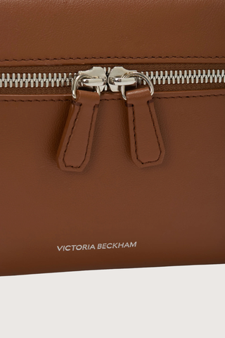 close up zipper and logo detail for Vanity Crossbody Bag tan 
Top handle
Removable crossbody strap
Microsuede lining
Top handle functionality
Zip closure
100% Calf Leather