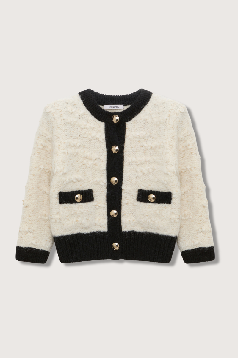 flat lay Delightful Sparkle Cardigan white with black thick trim on collar button closure cuff and pockets. large gold button closure. crewneck. Boxy style has a boucle-like feel and golden D-rose buttons