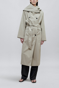 front profile model wearing coat buttoned Dorothy Trench Coat fog grey 
Dramatic oversized shawl collar drapes across the shoulders 
Double breasted closure with contrast buttons and self tie belt at the waist
Welt pockets at front
 dropped shoulders and bracelet length sleeves mid calf length cotton nylon blend