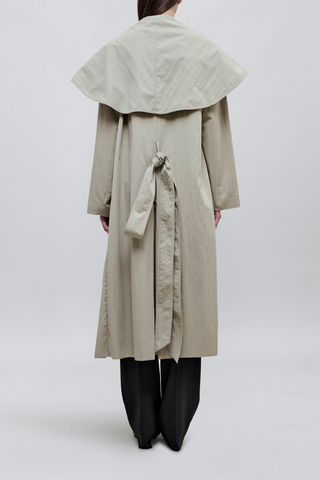 back profile model wearing Dorothy Trench Coat fog grey 
Dramatic oversized shawl collar drapes across the shoulders 
Double breasted closure with contrast buttons and self tie belt at the waist
Welt pockets at front
 dropped shoulders and bracelet length sleeves mid calf length cotton nylon blend