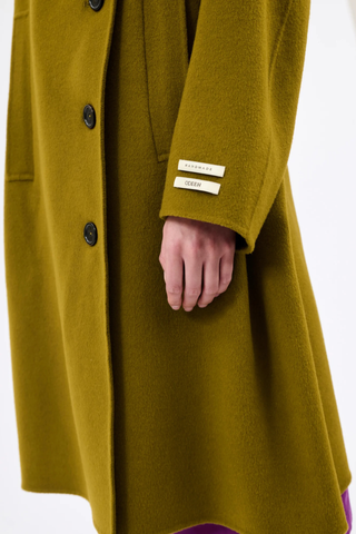 close up cuff tag detail for Double Face High Neck Coat malt Asymmetric coat
Offset button placket
Wide stand-up collar
Button fastening
Raglan sleeves
Vertical welt pockets
With tie belt
Material: 80% wool, 20% cashmere