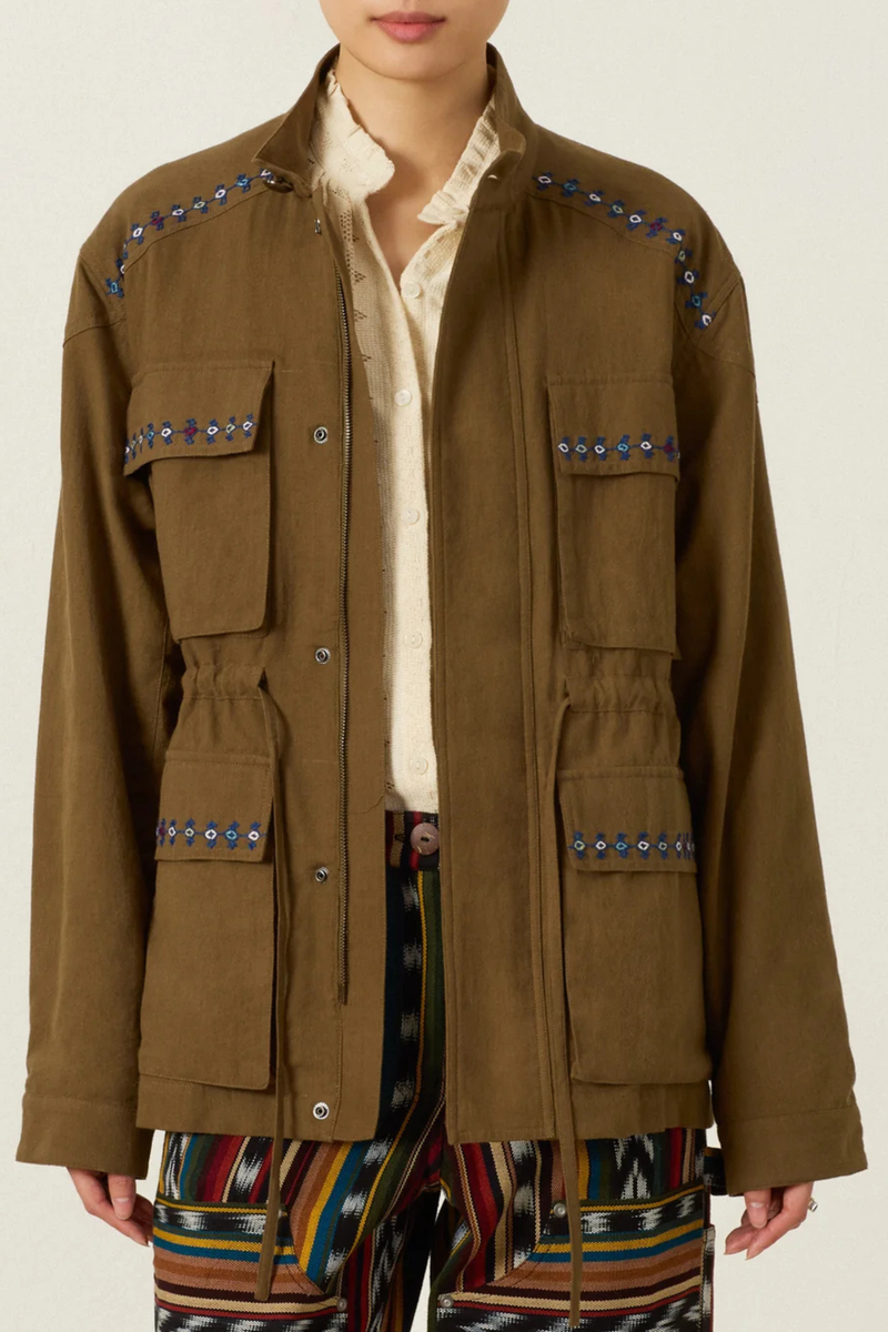 front profile model wearing  Evelyn Olive Branch Army Jacket dark green Cotton twill
Utility style jacket
Flap pockets
Drawstring waist
Trimmed with hand embroidery and lined in leopard print
Blue embroidery details on the shoulder and flap pockets
100% Khadi Cotton
Snap Front with hidden front zip
