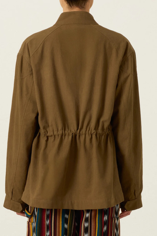 back profile model wearing  Evelyn Olive Branch Army Jacket dark green Cotton twill
Utility style jacket
Flap pockets
Drawstring waist
Trimmed with hand embroidery and lined in leopard print
Blue embroidery details on the shoulder and flap pockets
100% Khadi Cotton
Snap Front with hidden front zip