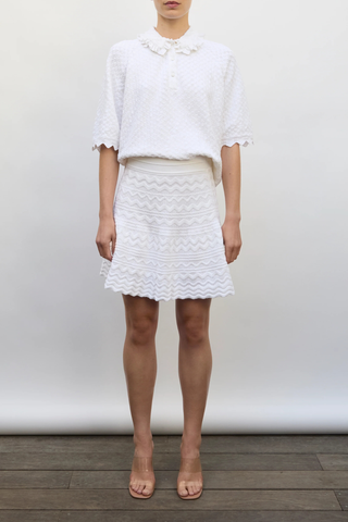 front profile model wearing Fantaisie Polo Top milk white 
Delicate, subtle, ultra-refined knit
Ruffle at the collar
Cuff details
Fine knit polo
Covered buttons
91% pure extra-soft cotton, 9% polyester
