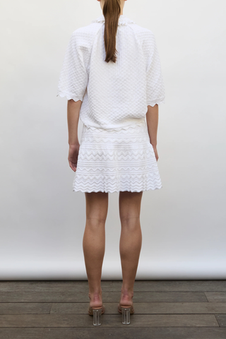 back profile model wearing Fantaisie Polo Top milk white 
Delicate, subtle, ultra-refined knit
Ruffle at the collar
Cuff details
Fine knit polo
Covered buttons
91% pure extra-soft cotton, 9% polyester