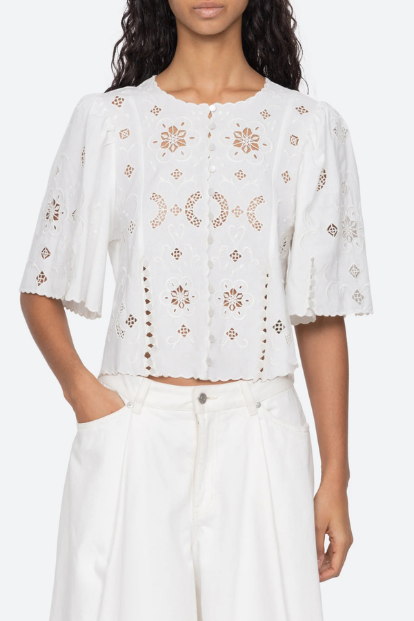 front profile model wearing Gardener Embroidered Short Sleeve Top white Eyelet detailing throughout
Scalloped edges
Flowing short sleeves
Cropped silhouette
Mother of pearl buttons
 cotton linen blenc