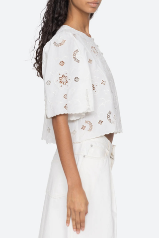 side profile model wearing Gardener Embroidered Short Sleeve Top white Eyelet detailing throughout
Scalloped edges
Flowing short sleeves
Cropped silhouette
Mother of pearl buttons
 cotton linen blenc