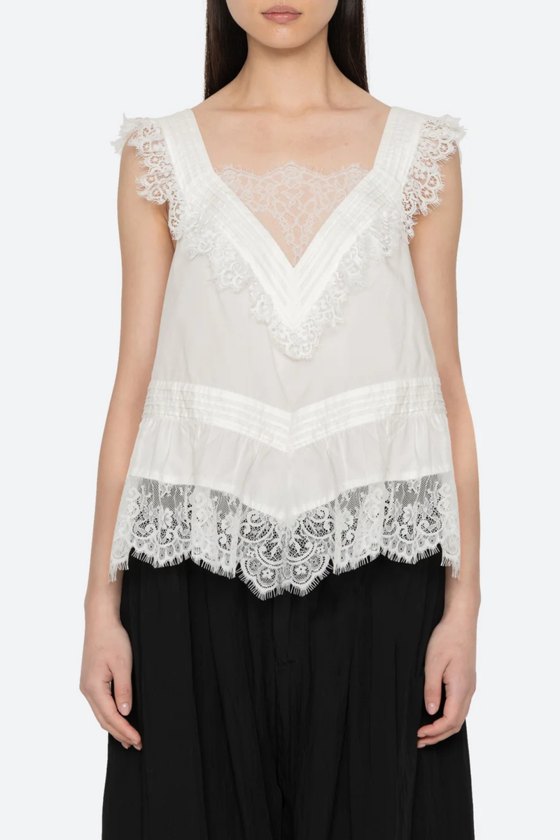 front profile model wearing  Hilda Solid Sleeveless Top White Soft v-neckline
Framed with floral lace trim
Fine pleated detailing
cotton nylon blend
Invisible side zipper