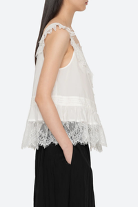 side profile model wearing  Hilda Solid Sleeveless Top White Soft v-neckline
Framed with floral lace trim
Fine pleated detailing
cotton nylon blend
Invisible side zipper