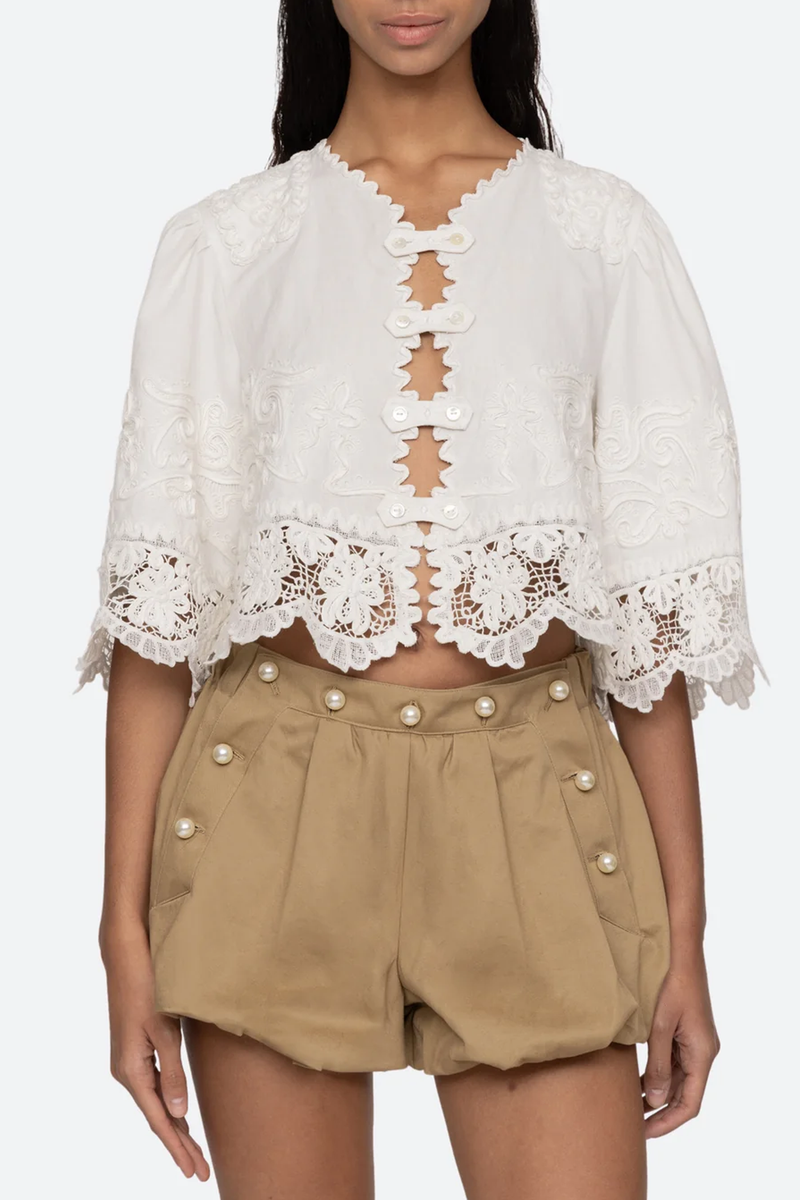 front profile model wearing Iyla Soutache Short Sleeve Top white with cropped silhouette and detailed button front closures.