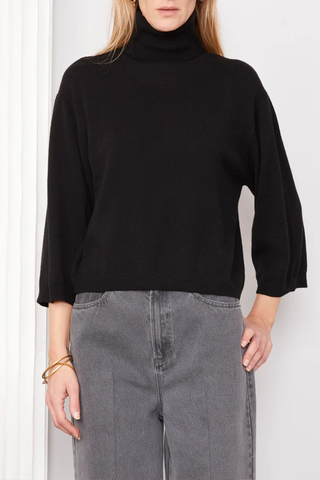 front profile model wearing Jalila Sweater Black wool cashmere Knitted long sleeves cardigan. Boxy fit. Front cover buttons closure. Jersery stitch on body and sleeves. Single rib at bottom and cuffs. Applied grosgrain ribbon under the button placket.