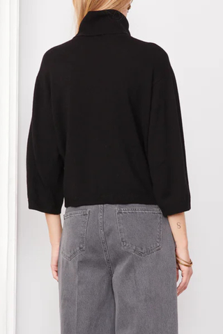 back profile model wearing Jalila Sweater Black wool cashmere Knitted long sleeves cardigan. Boxy fit. Front cover buttons closure. Jersery stitch on body and sleeves. Single rib at bottom and cuffs. Applied grosgrain ribbon under the button placket.