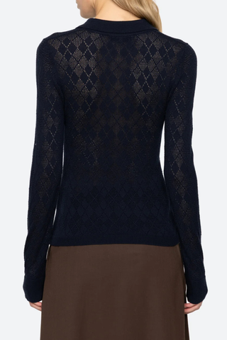 back profile model wearing  Jane Polo Sweater Navy Argyle polo sweater
Intricate argyle knit
Long sleeves
Custom patch at the sleeve
100% merino wool
Partial button front

Slimmer fit