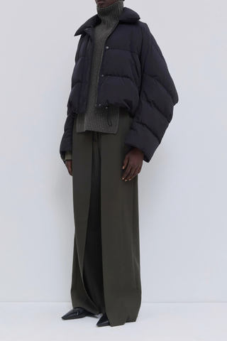 side profile model wearing Jani Puffer Jacket Black Cropped signature down jacket
Soft water-repellent nylon
Oversized silhouette
Voluminous sleeves
Statement collar
Concealed snap buttons
Zip closure
Adjustable drawcord hem
100% Nylon