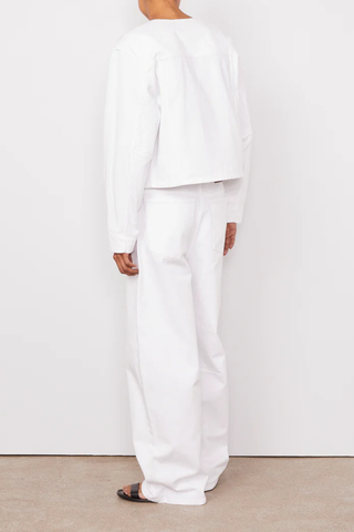 back profile model wearing  Joelle Jacket White Denim Short buttoned straight fit jacket
100% Oragnic Cotton
Round sleeves with darts and undersleeves yokes
Contrasted closing