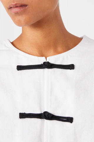 close up closure detail of  Joelle Jacket White Denim Short buttoned straight fit jacket
100% Oragnic Cotton
Round sleeves with darts and undersleeves yokes
Contrasted closing