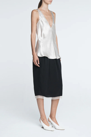 side profile model wearing  Lace Tulip Skirt Black
Elastic waistband
Hidden side pockets
Bouncy, lightweight Japanese Naia twill
Midi length
Slit at back
White lace hem
