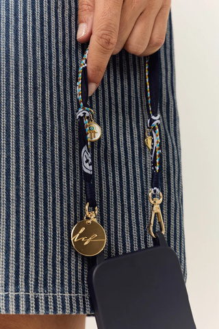 model wearing Laia Short Phone Chain Blue Short phone chain
Chain easily attaches to the rings of La Coque Francaise phone cases. If you don't have a ring case, a universal adapter is available - sold separately.

Composition: cotton voile and charms
Finishes: swivel carabiners and stainless steel rings
Length: 40 cm