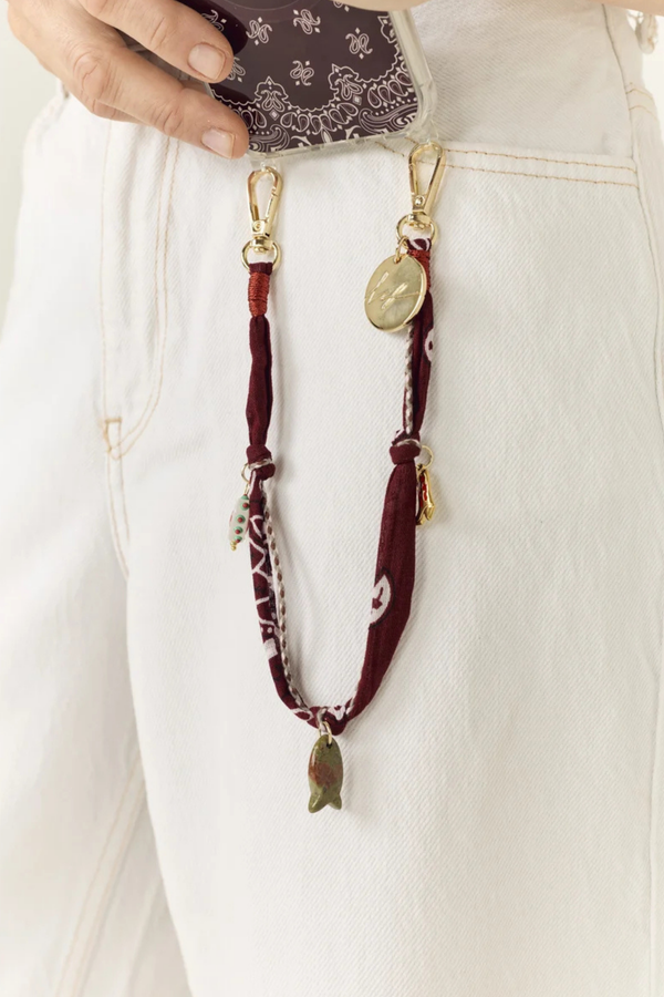 model wearing Laia Short Phone Chain Bordeaux Short phone chain
Chain easily attaches to the rings of La Coque Francaise phone cases
.If you don't have a ring case, a universal adapter is available - sold separately.

Composition: cotton voile and charms
Finishes: swivel carabiners and stainless steel rings
Length: 40 cm