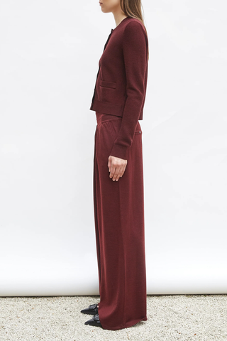 side profile model wearing Lauren Fluid Knit Trouser Amarante red Flowing knit pants Supple jersey knit Wide scalloped waistband Box pleats on the front