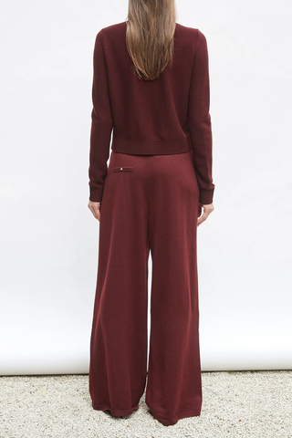 back profile model wearing Lauren Fluid Knit Trouser Amarante red Flowing knit pants Supple jersey knit Wide scalloped waistband Box pleats on the front
