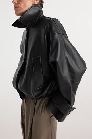 angled profile with the collar up model wearing Leather Blouson Jacket black Cropped bomber jacket
Dropped shoulders
Wide sleeves
Sleeve straps
Button closures
Sculptural silhouette
100% leather