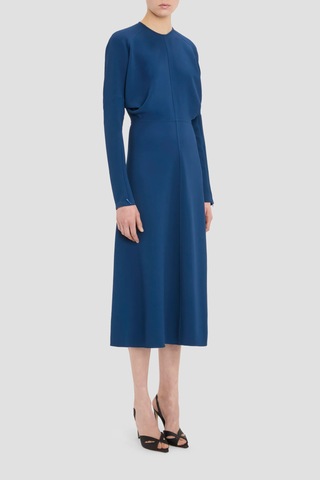 side profile model wearing long Sleeve Dolman Midi Dress Dark Ocean blue Dolman long sleeve
Round neckline
Defined waist
Draped feature at sleeve underarm, fitted sleeve through the forearm
Midi length 
Tonal topstitching
voluminous underarm drape
Fitted at the waist and more relaxed fit through bodice and hip
