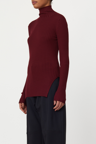 side profile model wearing Long Sleeve Merino wool T-Neck sweater burgundy, Fitted ribbed turtle neck sweater, High side slit