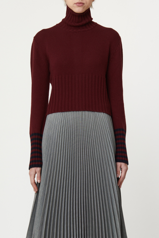 front profile model wearing Long Sleeve T-neck Button Back Sweater burgundy wool, Turtleneck
Button back detail, Covered buttons, Horizontal stripe detail on cuff, Thick ribbed hem and cuff, Shrunken cropped fit