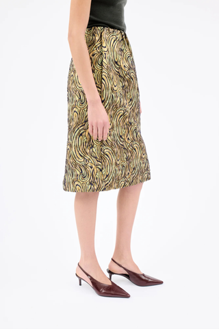 side profile model wearing  Lurex Paisley Wave Pencil Skirt greengold Knee-length skirt
Straight cut
Sewn-in elastic waistband
Side-seam pockets
High slit at the back
Center-back zipper with ribbon pull
Material: 73% polyester, 27% polyamide
